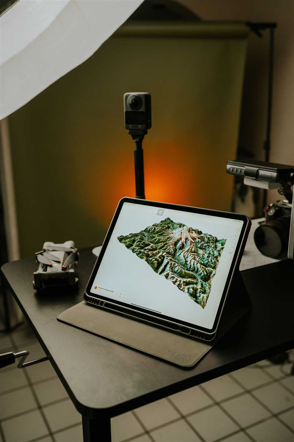 Tablette affichant un relevé 3D de terrain, à côté du drone replié